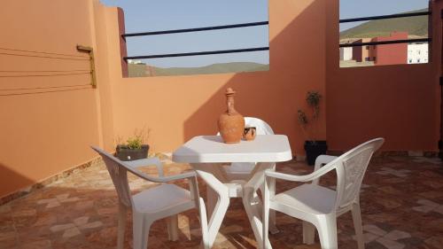 une table blanche avec deux chaises et un vase sur elle dans l'établissement la perle rare de Sidi Ifni, à Sidi Ifni