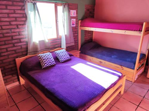 Habitación con litera y sábanas moradas. en Cabaña Los Lúpulos en El Bolsón
