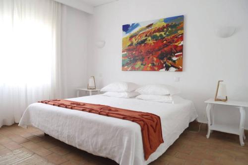 a bedroom with a white bed with a blanket on it at Laranjal Farm House - Casa da Lareira in Faro