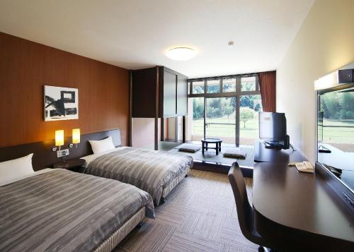 a hotel room with two beds and a desk at Route Inn Grantia Fukuoka Miyawaka - Wakita Onsen in Miyawaka