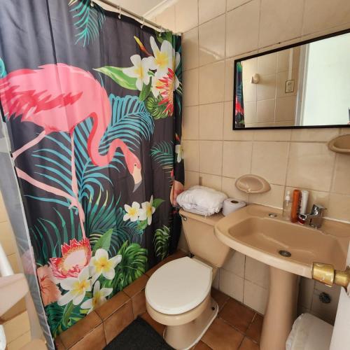 a bathroom with a shower curtain with a toilet and a sink at Casa Portal Del Valle in La Serena