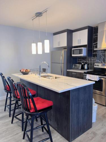 a kitchen with a large island with red cushioned chairs at Banff Garden Suite&2mins Bus station Close LRT& Free Parking in Calgary