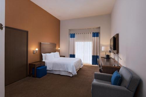 um quarto de hotel com uma cama e uma cadeira em Four Points by Sheraton Galerias Monterrey em Monterrey