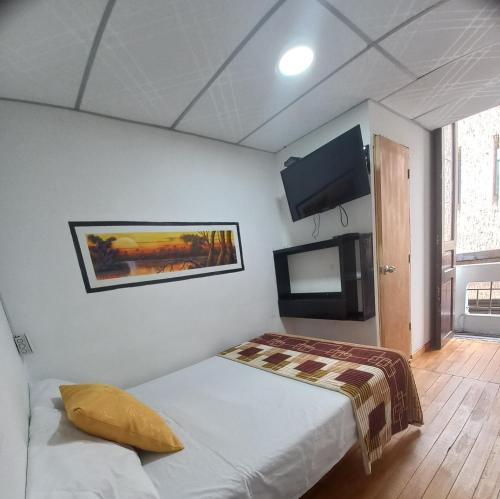 a bedroom with a bed and a flat screen tv at Hotel Slow Montecarlo in Manizales