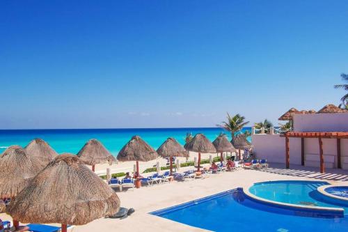 a beach with umbrellas and chairs and the ocean at Villa Aurora Beautiful Beachfront Apartment in Cancún