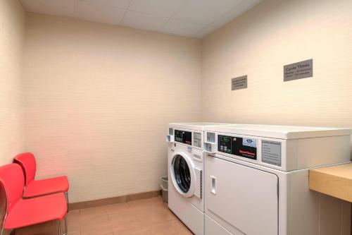 a laundry room with a washing machine and a red chair at Comfort Inn & Suites Green Bay Stadium Area in Green Bay