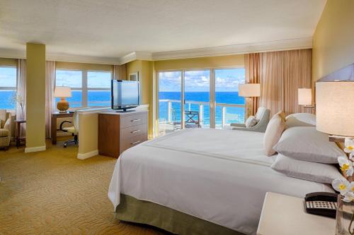 a hotel room with a bed and a desk with a television at Fort Lauderdale Marriott Pompano Beach Resort and Spa in Pompano Beach