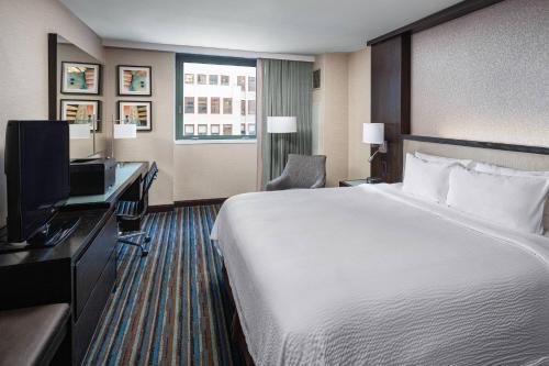 a hotel room with a bed and a desk and a television at Courtyard New York Manhattan/Times Square in New York