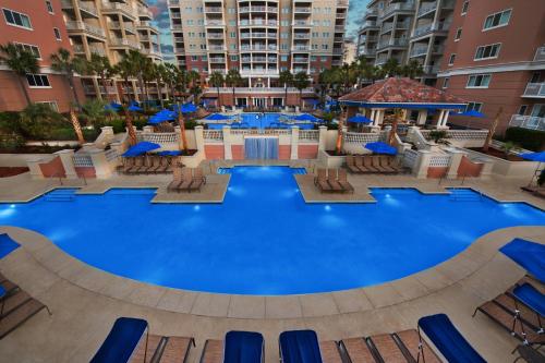 a large swimming pool with chairs and blue umbrellas at Marriott's OceanWatch Villas at Grande Dunes in Myrtle Beach