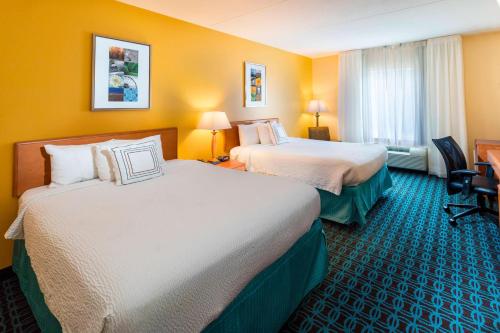 two beds in a hotel room with yellow walls at Fairfield Inn & Suites Marianna in Marianna