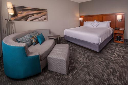 スターリングにあるCourtyard by Marriott Dulles Town Centerのベッド1台、ベッド1台、ソファ1台が備わるホテルルームです。
