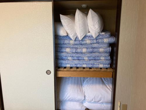ein Schrank mit blauen und weißen Decken und Kissen in der Unterkunft Route Inn Grantia Fukuoka Miyawaka - Wakita Onsen in Miyawaka