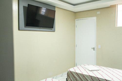 a bedroom with a flat screen tv on the wall at Hotel Tenda Obsession in São Paulo