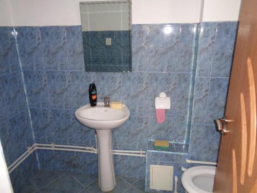 a blue tiled bathroom with a sink and a toilet at Gasthaus Enduro Bica in Caransebeş