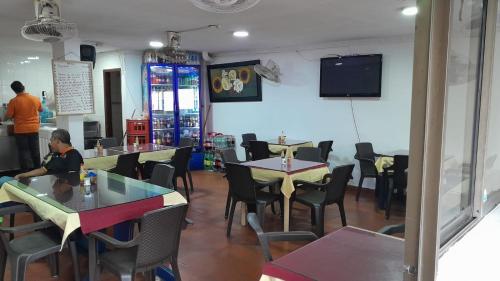 ein Restaurant mit Tischen und Stühlen und einem TV an der Wand in der Unterkunft Hotel Danes Barranquilla in Barranquilla