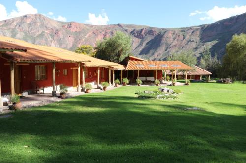 a house with a green yard with mountains in the background at Hotel Villa Urubamba in Urubamba