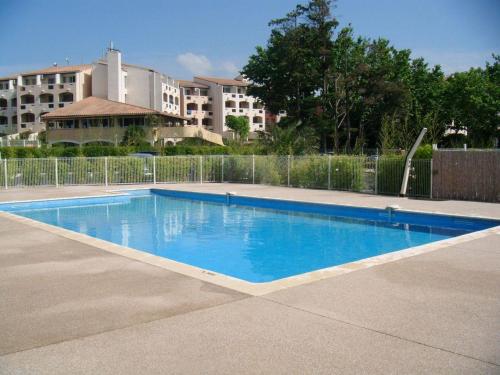 une grande piscine bleue devant un immeuble dans l'établissement Superbe appartement au Cap d'Agde, piscine et parking - FR-1-723-3, au Cap d'Agde