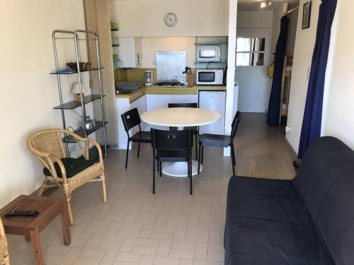 un salon avec une table et des chaises et une cuisine dans l'établissement Cap d'Agde : T2 spacieux, parking, balcon, piscine, proche commerces et plage - FR-1-723-19, au Cap d'Agde
