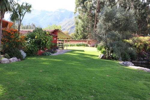 a yard with a green lawn with a house at Hotel Villa Urubamba in Urubamba
