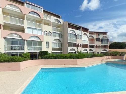 un grand immeuble d'appartements avec une grande piscine dans l'établissement Appartement proche plage Richelieu avec piscine, clim et parking - FR-1-723-14, au Cap d'Agde