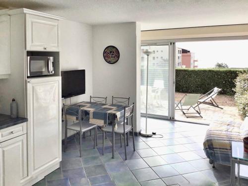 Il dispose d'un balcon et d'une cuisine avec une table et des chaises. dans l'établissement Appartement Rez-de-Jardin 5 Pers, 2min Plage, Terrasse, Vue Mer, Garage - FR-1-723-26, au Cap d'Agde