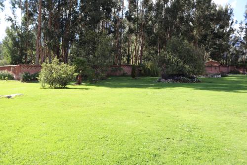 a large yard with green grass and trees at Hotel Villa Urubamba in Urubamba