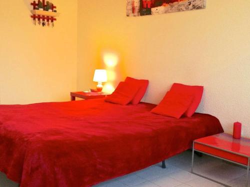- un lit rouge avec deux oreillers rouges dans une chambre dans l'établissement Studio cabine avec piscine, parking, climatisation, proche plage - FR-1-723-30, au Cap d'Agde