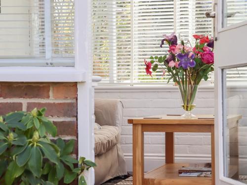 a vase of flowers on a table in a living room at Paddock View in Maidstone