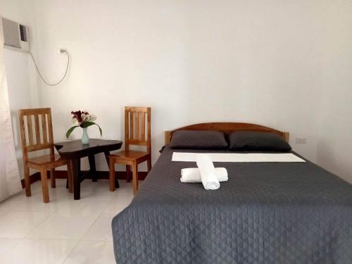 a bedroom with a bed and a table and chairs at Jazz Ferme Inn Batuan Bohol in Batuan