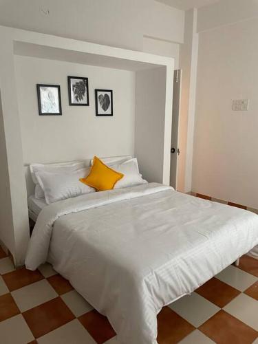 プネにあるAndrews Villaのベッドルーム(白い大型ベッド、黄色い枕付)