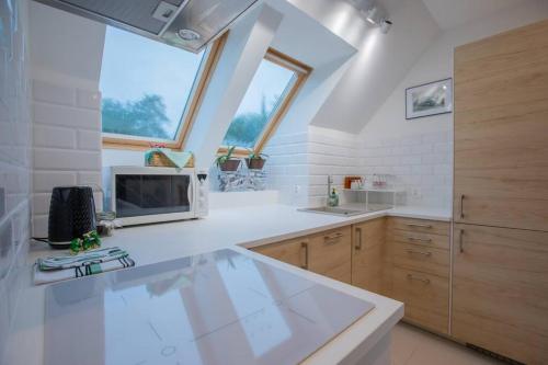 a kitchen with a white counter top and some windows at Urban Jungle Taras- luksusowy apartament w Gdyni. in Gdynia