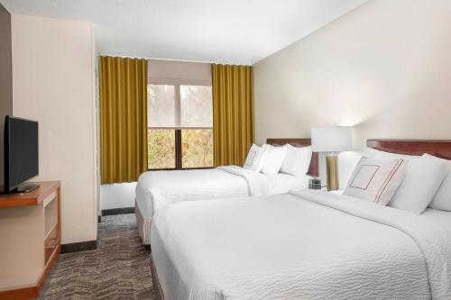 a hotel room with two beds and a flat screen tv at SpringHill Suites Asheville in Asheville