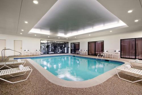 a large swimming pool with two chairs and a table at Courtyard St. Louis Airport/Earth City in Bridgeton