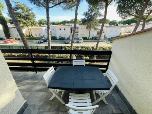 d'une table et de chaises sur un balcon avec vue sur la rue. dans l'établissement Appartement calme avec piscine, pinède, parking, 5 pers, Cap d'Agde - FR-1-723-85, au Cap d'Agde