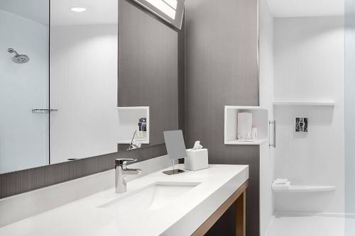 Baño blanco con lavabo y espejo en Courtyard by Marriott Wayne Fairfield en Wayne