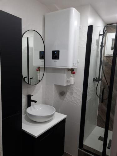 une salle de bain blanche avec un lavabo et un miroir dans l'établissement Charmant appartement proche de la défense, à Rueil-Malmaison