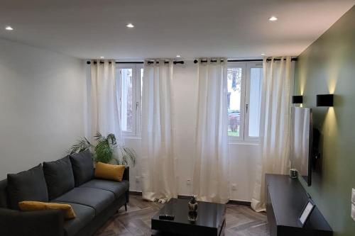 - un salon avec un canapé et quelques fenêtres dans l'établissement Charmant appartement proche de la défense, à Rueil-Malmaison