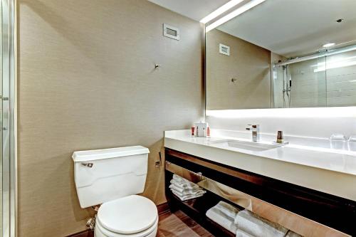 a bathroom with a toilet and a sink and a mirror at Tulsa Marriott Southern Hills in Tulsa