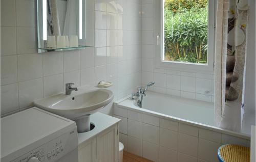 een witte badkamer met een wastafel, een bad en een raam bij Amazing Home In Portiragnes With Outdoor Swimming Pool in Portiragnes