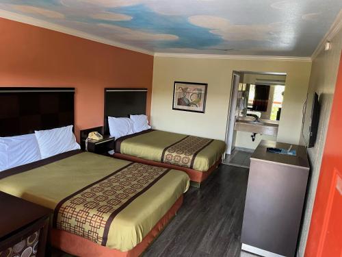 a hotel room with two beds and a bathroom at Rivera Inn & Suites Motel in Pico Rivera