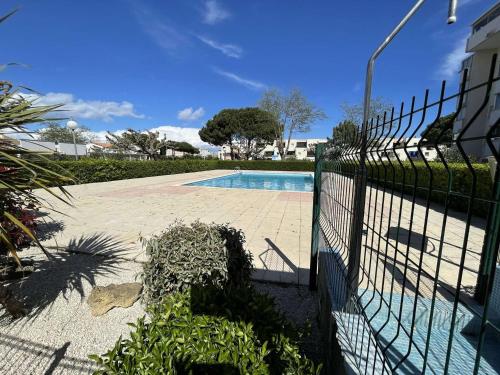 une clôture en face d'une piscine dans l'établissement Appartement 2 pièces avec loggia et piscine à 100m de la plage - Le Grau-du-Roi - FR-1-250-250, au Grau-du-Roi
