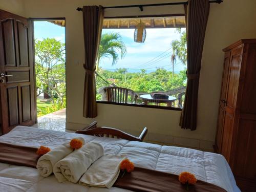 1 dormitorio con 1 cama con toallas y ventana en Frangipani Inn & Restaurant, en Seraya