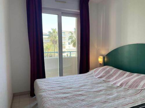 une chambre avec un lit et une grande fenêtre dans l'établissement Appartement avec terrasse, piscine et à 5 min de la plage à Juan les Pins - FR-1-252-185, à Antibes