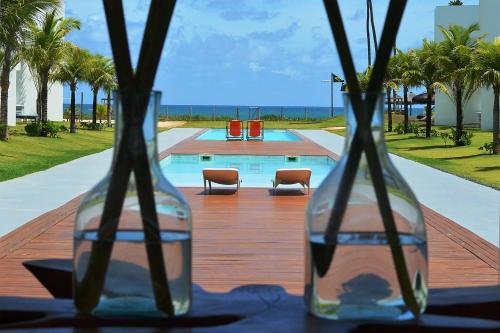 two glass vases sitting on a table with a pool at B Blue Beachouses in Itacimirim