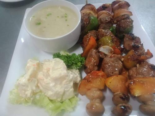 a plate of food with meat and vegetables and a dipping sauce at Arizona Beach Resort, Subic Bay, Philippines 2200 in Olongapo