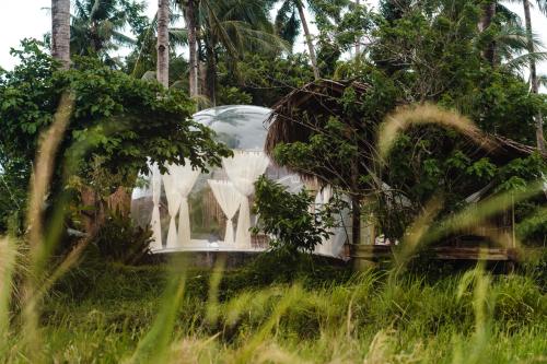 a white house with a glass dome in the grass at Bubble Siargao in General Luna