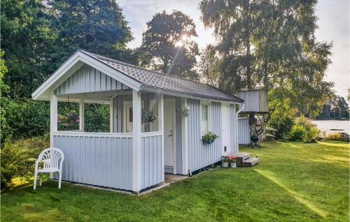 a white shed with a chair in a yard at Gorgeous Home In Ljung With Kitchen in Ljung
