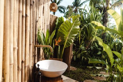 a bathroom with a sink next to a fence with plants at Bubble Siargao in General Luna