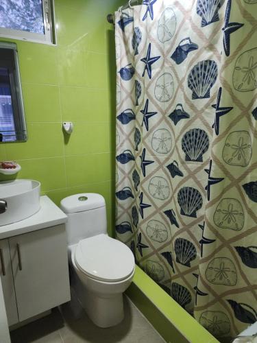 y baño con aseo y cortina de ducha. en 2 bedrooms, 2 bathrooms, pool and near from the beach, en Juan Dolio