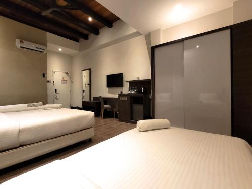 a bedroom with two beds and a desk with a computer at The NINES HOTEL Malacca in Malacca